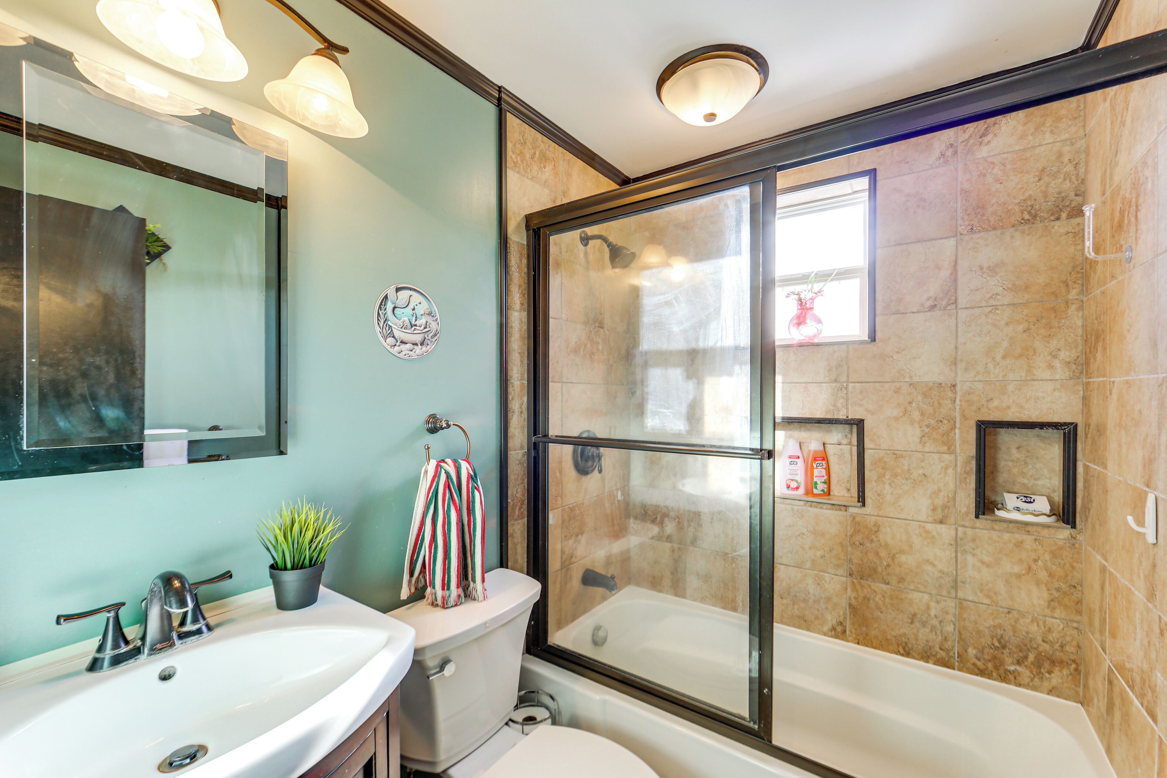 A bathroom with a glass-enclosed shower, a sink, a toilet, and a mirror.