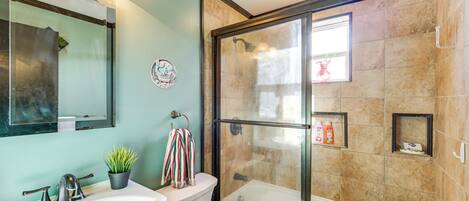 A bathroom with a glass-enclosed shower, a sink, a toilet, and a mirror.