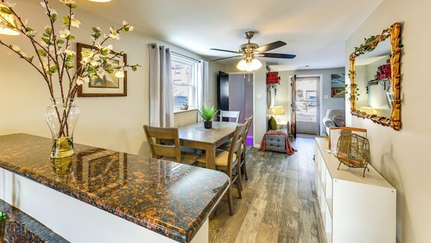 A modern kitchen with granite countertops, wooden dining table, and chairs. There is a ceiling fan, a vase with branches, and a mirror on the wall. - Pet Friendly, Private! Multi-level Brookline Home (Pittsburgh)