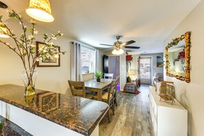 A modern kitchen with granite countertops, wooden dining table, and chairs. There is a ceiling fan, a vase with branches, and a mirror on the wall. - Pet Friendly, Private! Multi-level Brookline Home (Pittsburgh)
