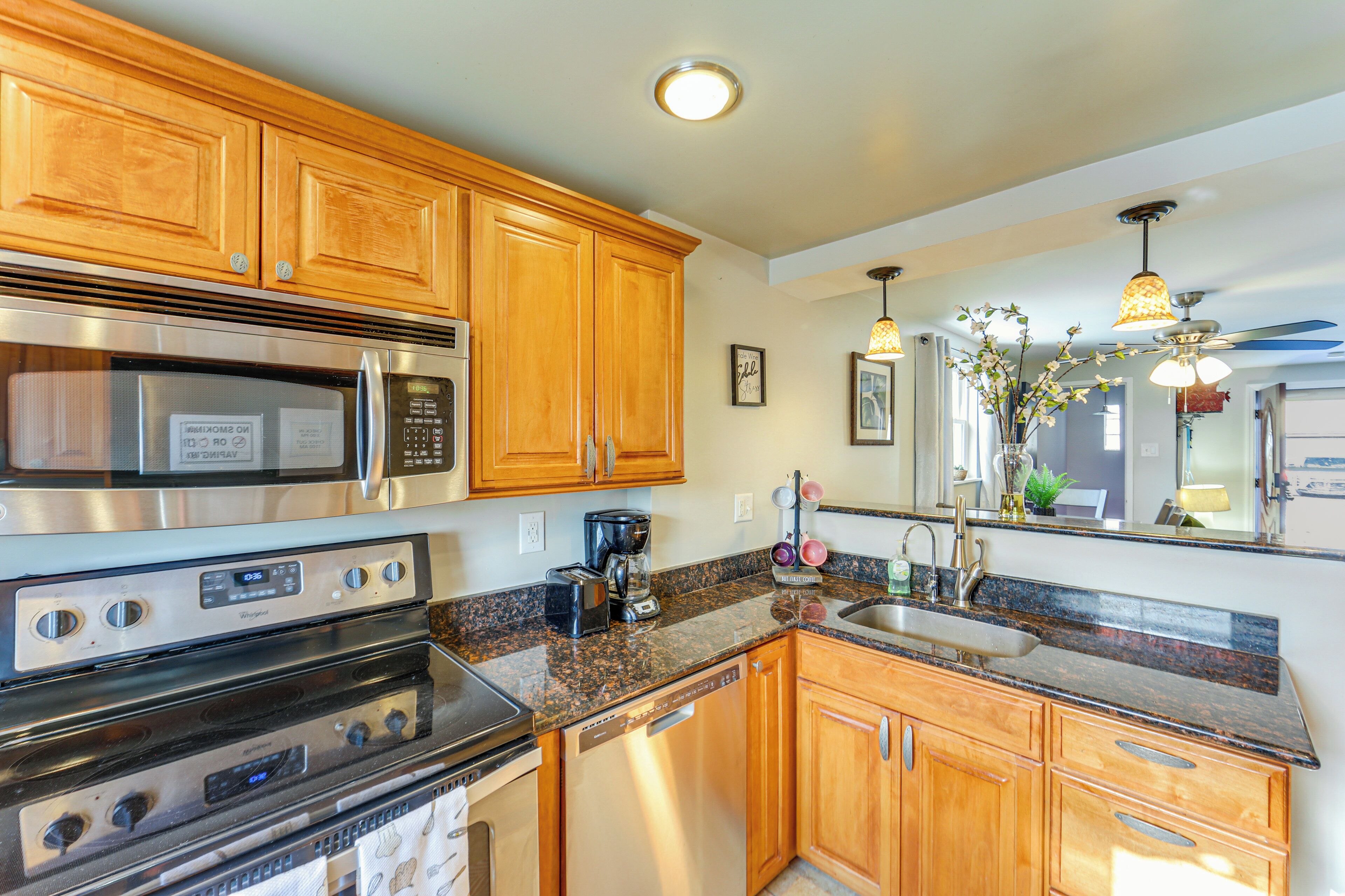 A kitchen with wooden cabinets, stainless steel appliances, granite countertops, and a built-in dishwasher.