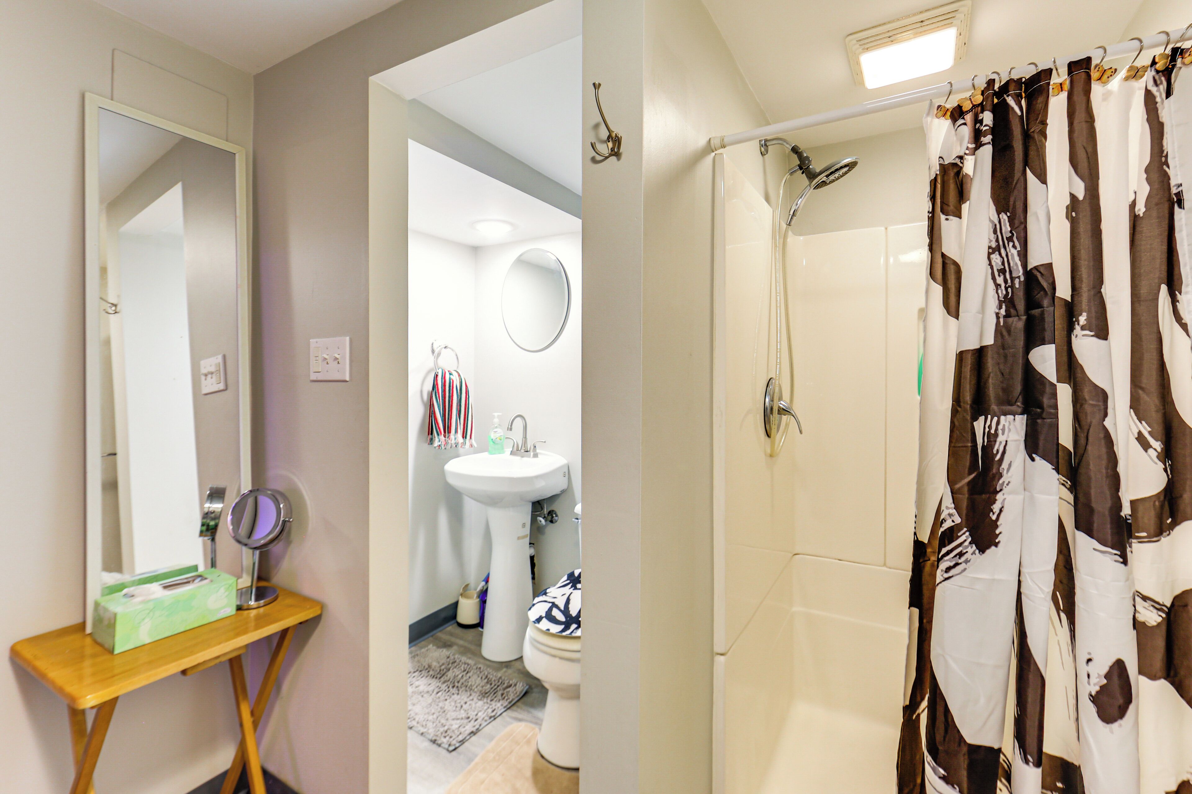 A bathroom with a mirror, sink, toilet, and shower curtain.