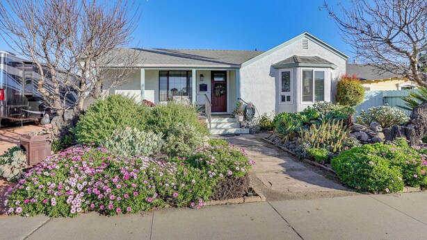 A single-story house with a front porch, a garage, and a well-maintained garden with various plants and flowers. - Couples Retreat in Lompoc! Studio w/ Lush Garden (Lompoc)