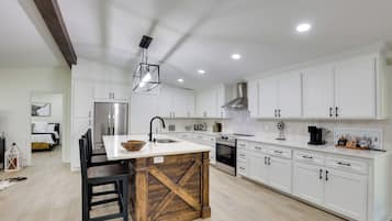 A modern kitchen with white cabinetry, a central island, and a farmhouse-style cross beam.