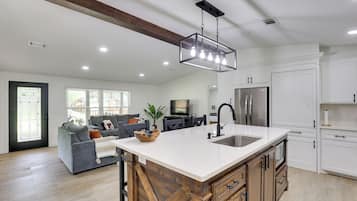A modern kitchen with a large island, stainless steel appliances, and a farmhouse-style ceiling.