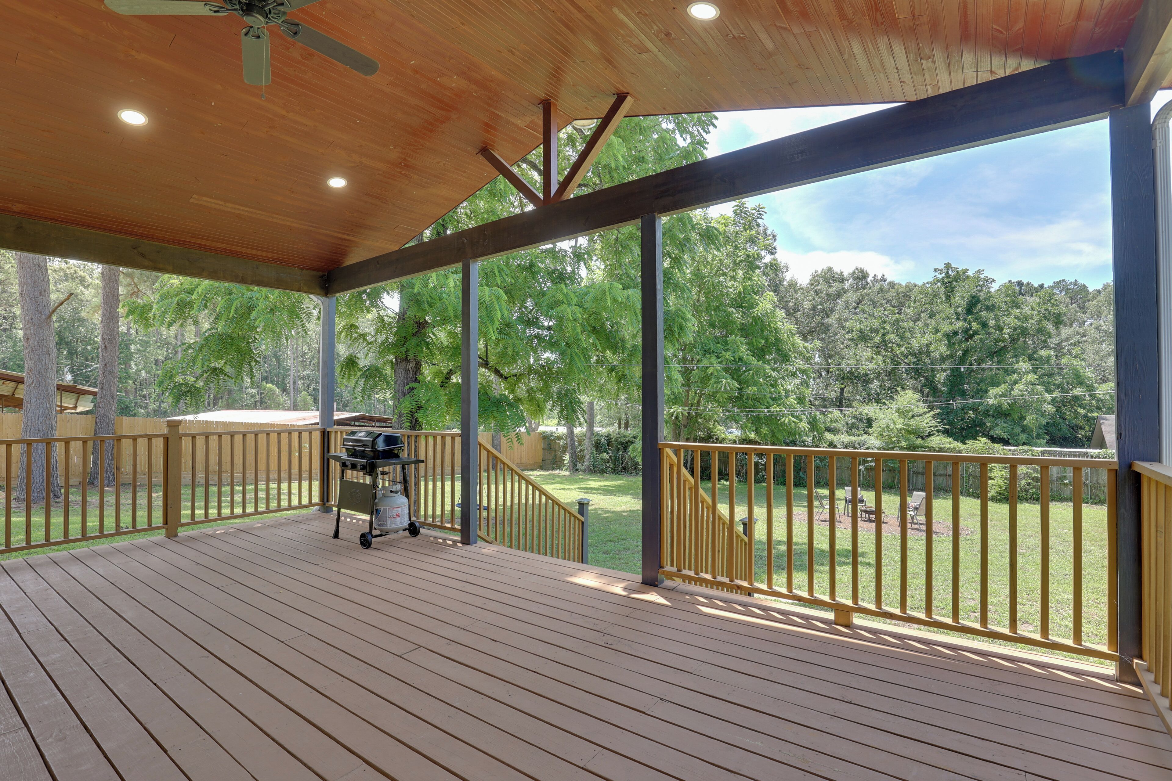 A covered deck with a view of a grassy yard and trees.