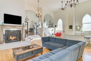 Een ruime woonkamer met een open haard, een grote hoekbank en een televisie.