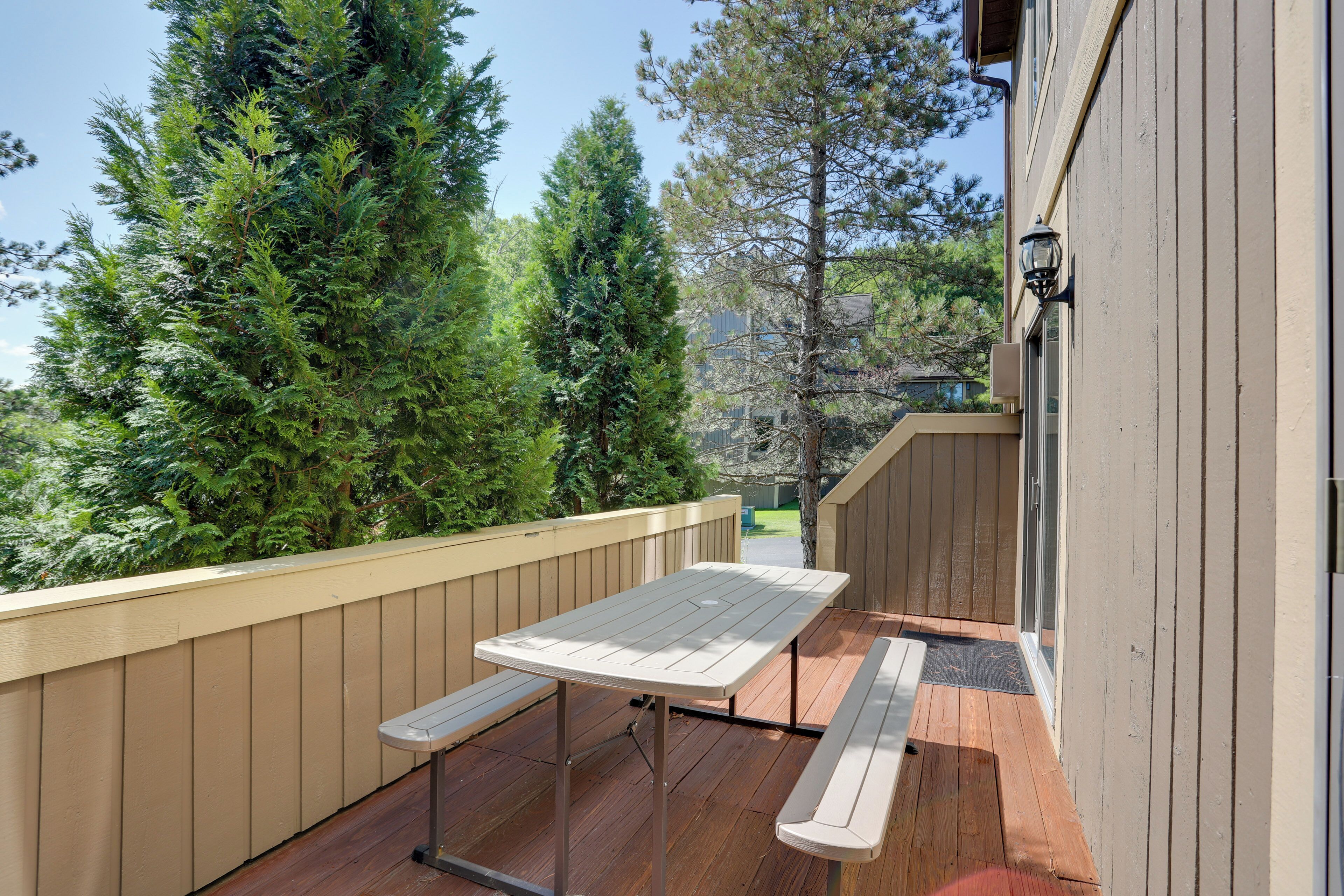 A wooden deck with a picnic table and benches, surrounded by trees.