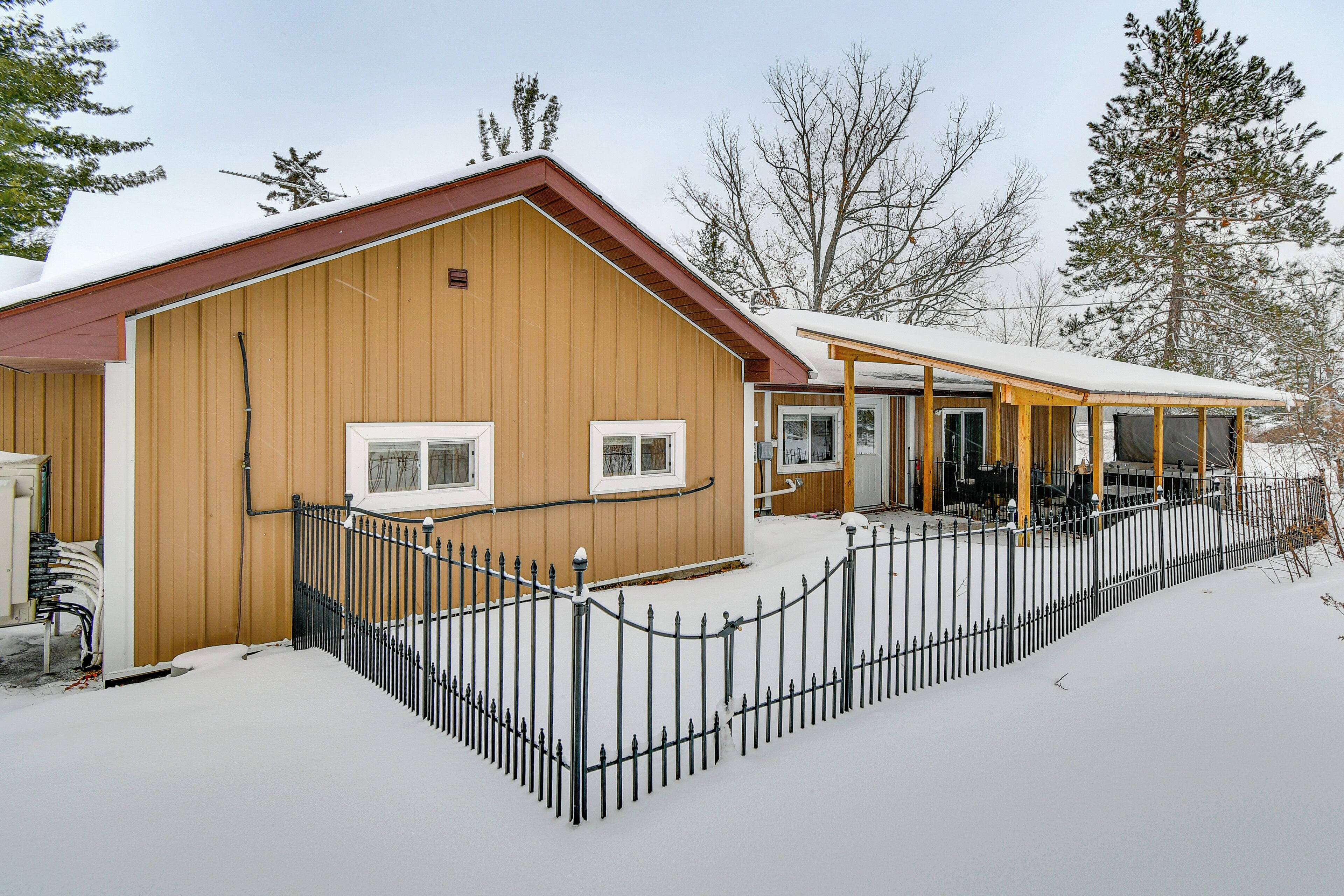 A wooden building with a covered porch and a fenced area.