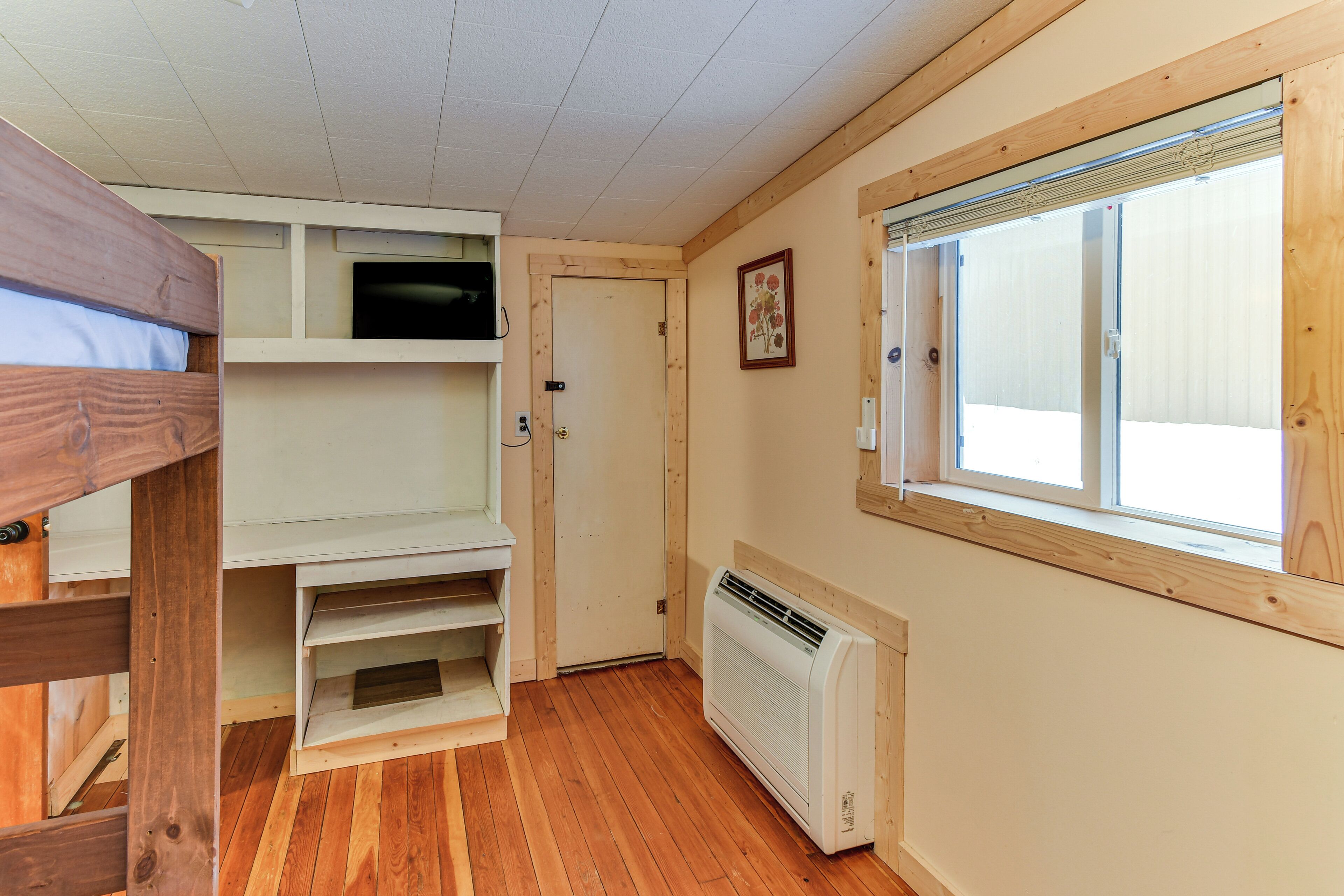 Una habitación con literas, estante empotrado, radiador y ventana con persianas.