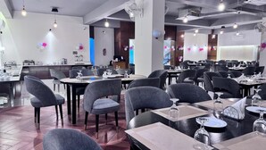 A restaurant with multiple tables and chairs, a kitchen area in the background, and balloons on the walls. - Grand Khalifa Hotel Hamama (Sylhet)