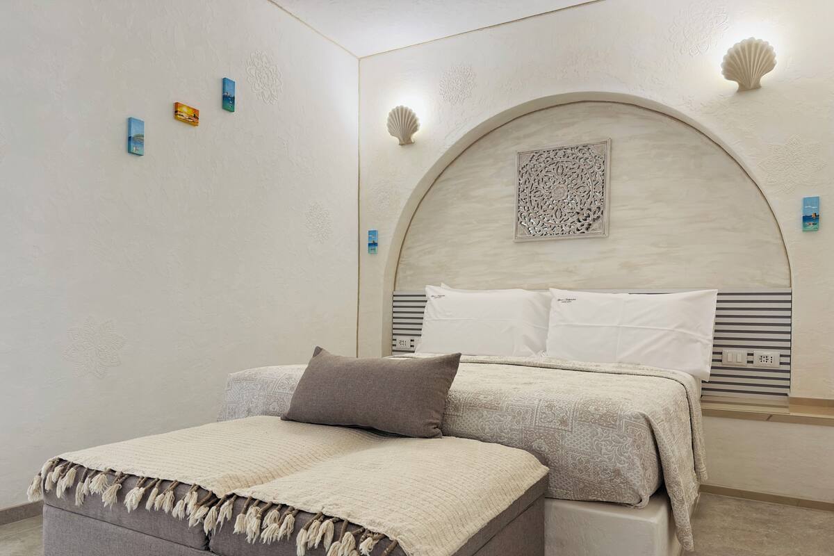 A bedroom with a bed, a bedside table, and a decorative headboard.
