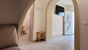 Un pasillo interior con un sofá, un taburete de madera y una puerta de diseño único.