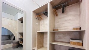 Un interior moderno con estanterías empotradas de madera, una zona de estar con sofá y reposapiés, y un espejo grande que refleja el espacio.
