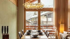 Un coin repas avec une grande fenêtre donnant sur une montagne enneigée.