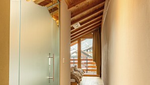Un couloir avec des poutres en bois, une porte vitrée et un lit donnant sur l’extérieur.