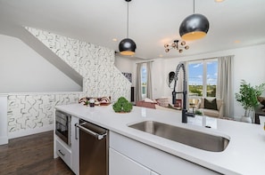 A modern kitchen with a white countertop, stainless steel sink, and black pendant lights. - 3 Side-by-Side Homes | 12BR | 3 Rooftop Hot Tubs (nashville)