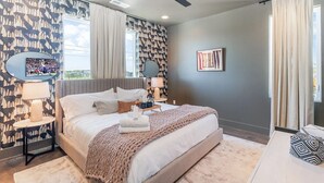 Een moderne slaapkamer met een groot bed, twee nachtkastjes, een plafondventilator en een televisie aan de muur.