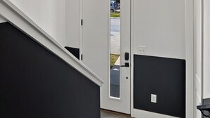 Un couloir avec un mur noir et blanc, une porte dotée d’une fenêtre et un escalier.