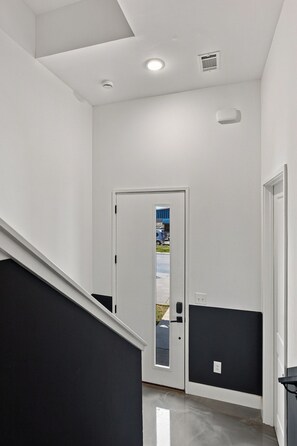 Ein Flur mit Wand in Schwarzweiß, einer Tür mit Fenster und einer Treppe.