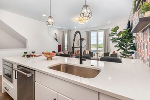 A modern kitchen with a large island, stainless steel appliances, and pendant lighting. - Stylish 4BR Oasis w/ Hot Tub + City Views (nashville)