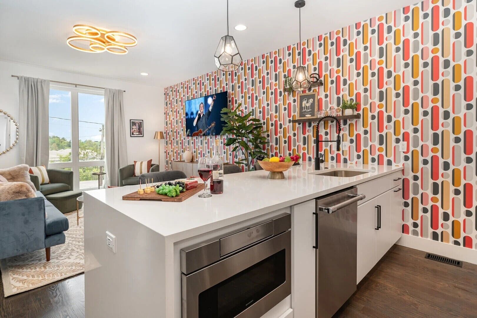 A modern kitchen with a large island, stainless steel appliances, and a colorful abstract wall pattern.
