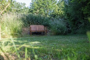 A wooden bench in a grassy area surrounded by dense foliage. - Yart (Scharendijke)