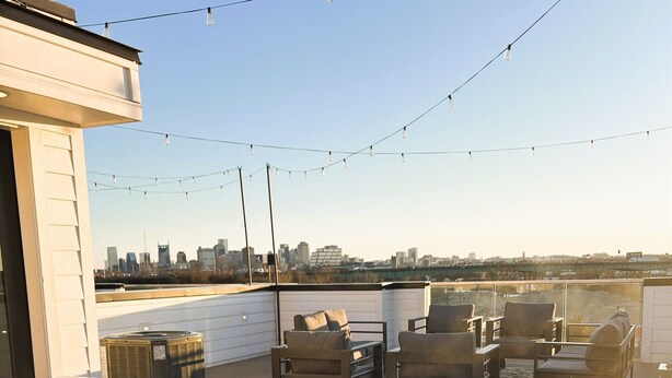 En takterrass med ett bubbelbad, utomhusmöbler och utsikt över stadens skyline.