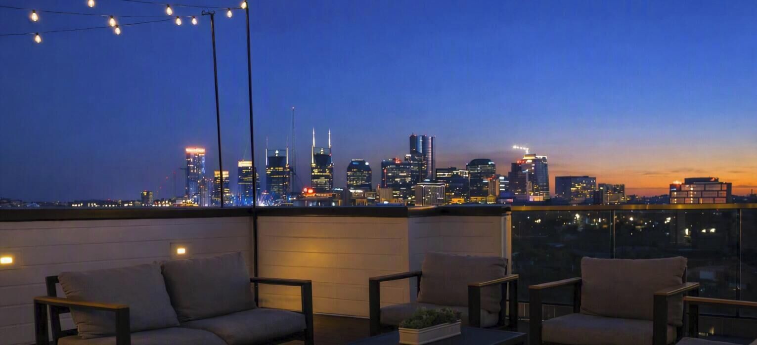 Eine Dachterrasse mit Sitzgelegenheiten und Blick auf die Skyline in der Abenddämmerung.