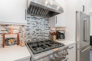 A modern kitchen with a gas stove, stainless steel appliances, and a tiled backsplash. - Spacious 4BR Luxury Stay w/ Rooftop Hot Tub (nashville)