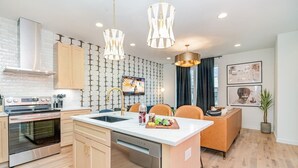 Una cocina moderna con una isla central, electrodomésticos de acero inoxidable e iluminación colgante.