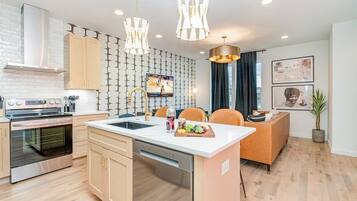 A modern kitchen with a central island, stainless steel appliances, and pendant lighting.