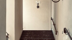 Un escalier avec des marches en marbre et une rampe, menant à un plafond en arc de cercle.