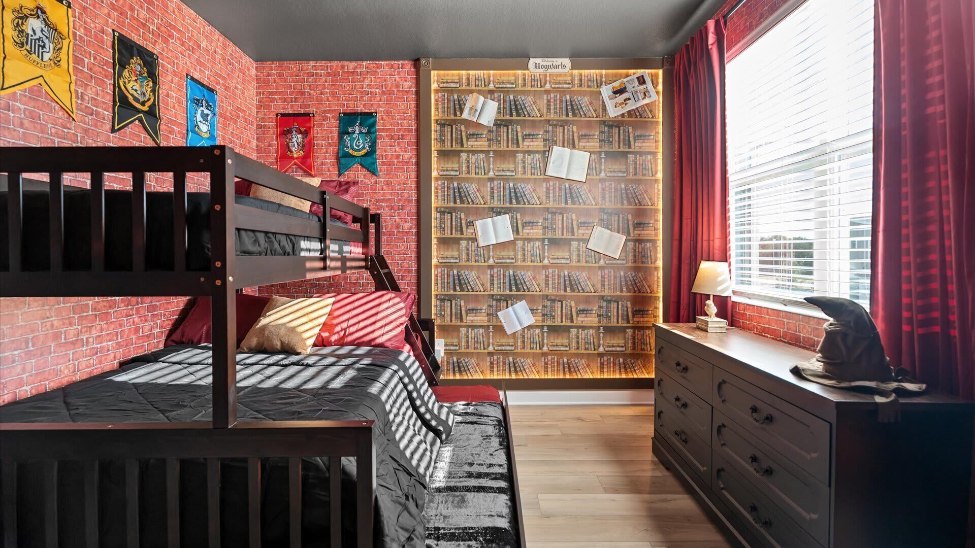 A room with a bunk bed, a bookshelf, and a window with curtains.