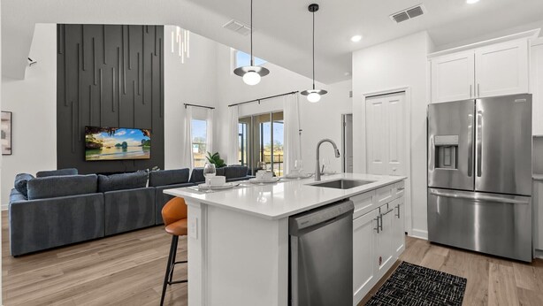 A modern kitchen with a stainless steel refrigerator, a built-in dishwasher, and a large island with a sink. - Family 5BR Villa w Pool Theatre Reunion Village (Kissimmee)