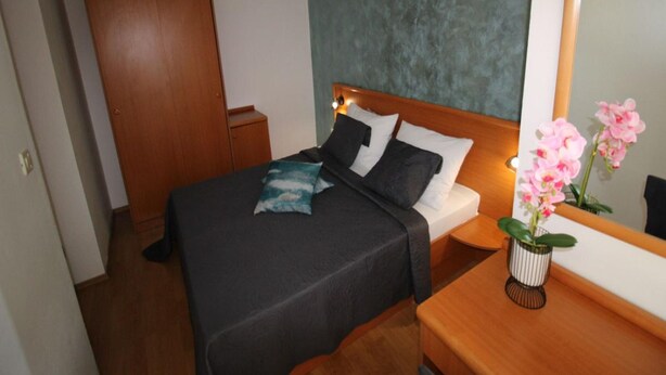 A neatly arranged bedroom with a bed, bedside table, and a mirror. - Charming Apartment in Stara Novalja (Novalja)