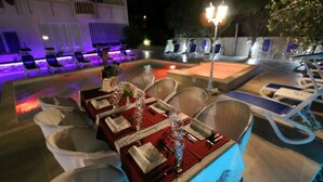 An outdoor dining area with a table set for four, surrounded by white cushioned chairs. - Charming Apartment in Stara Novalja (Novalja)