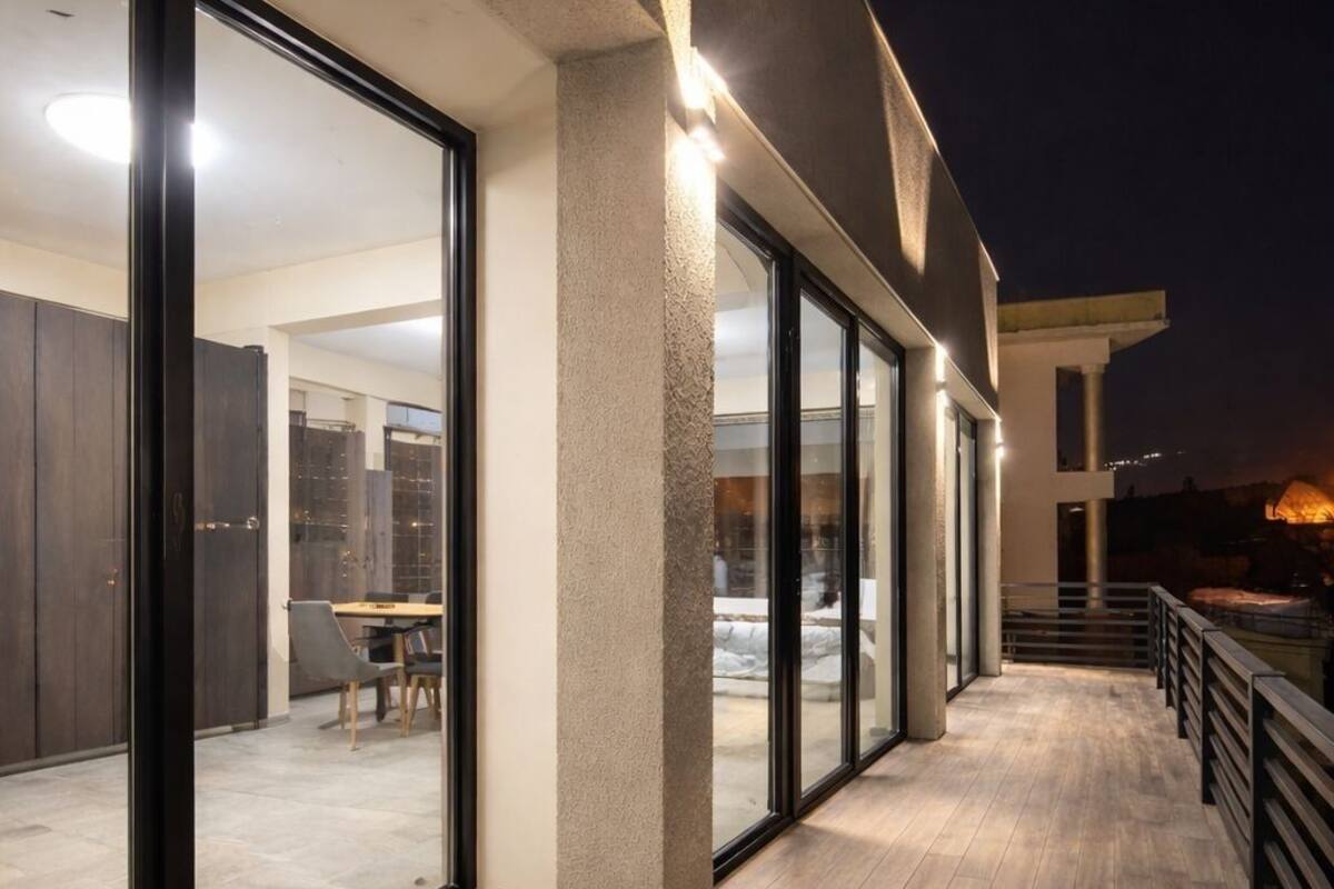A modern building exterior with large glass doors leading to an interior space, a wooden deck, and a railing.
