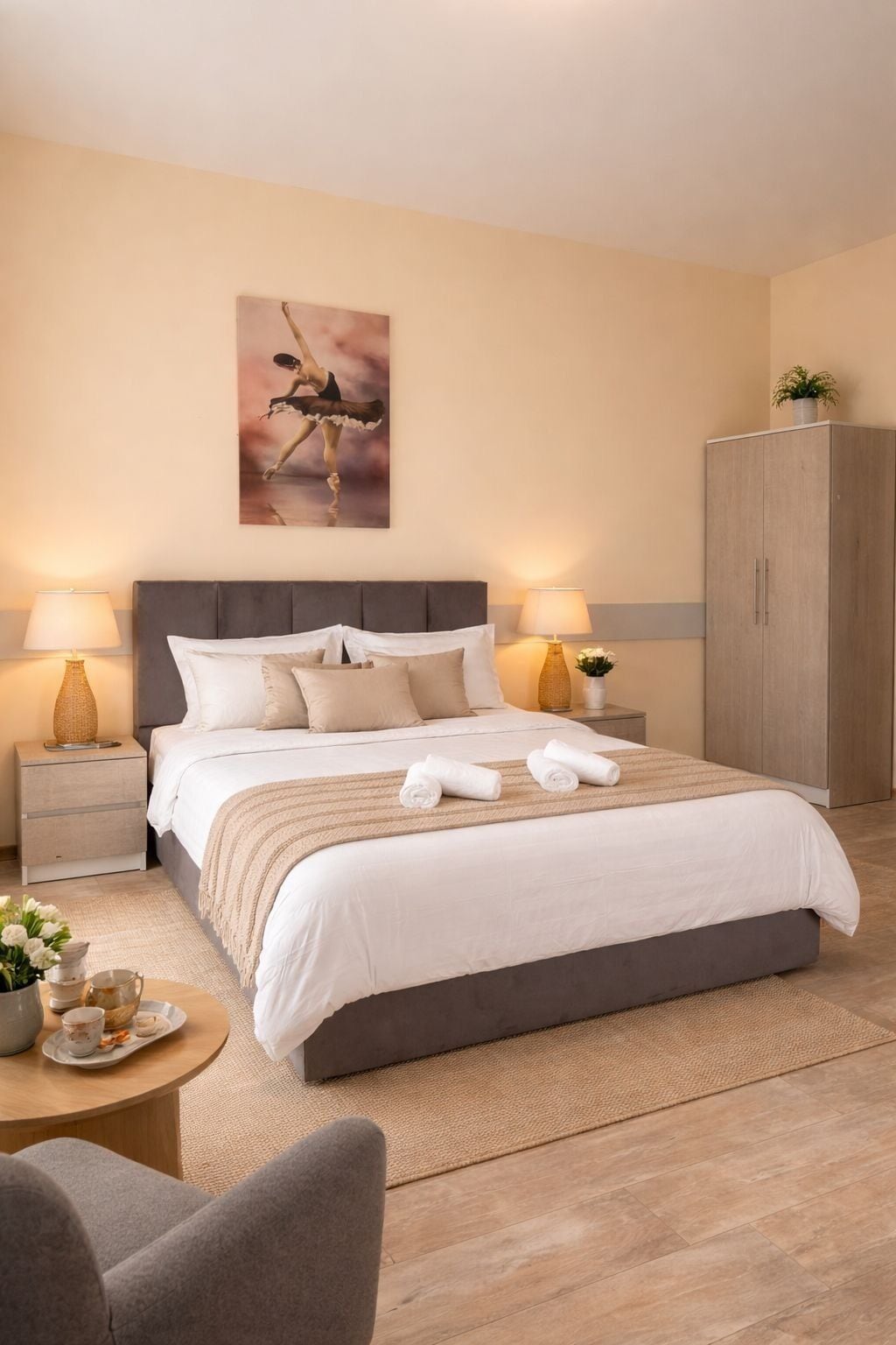A bedroom with a large bed, two bedside tables with lamps, a wardrobe, and a painting on the wall.