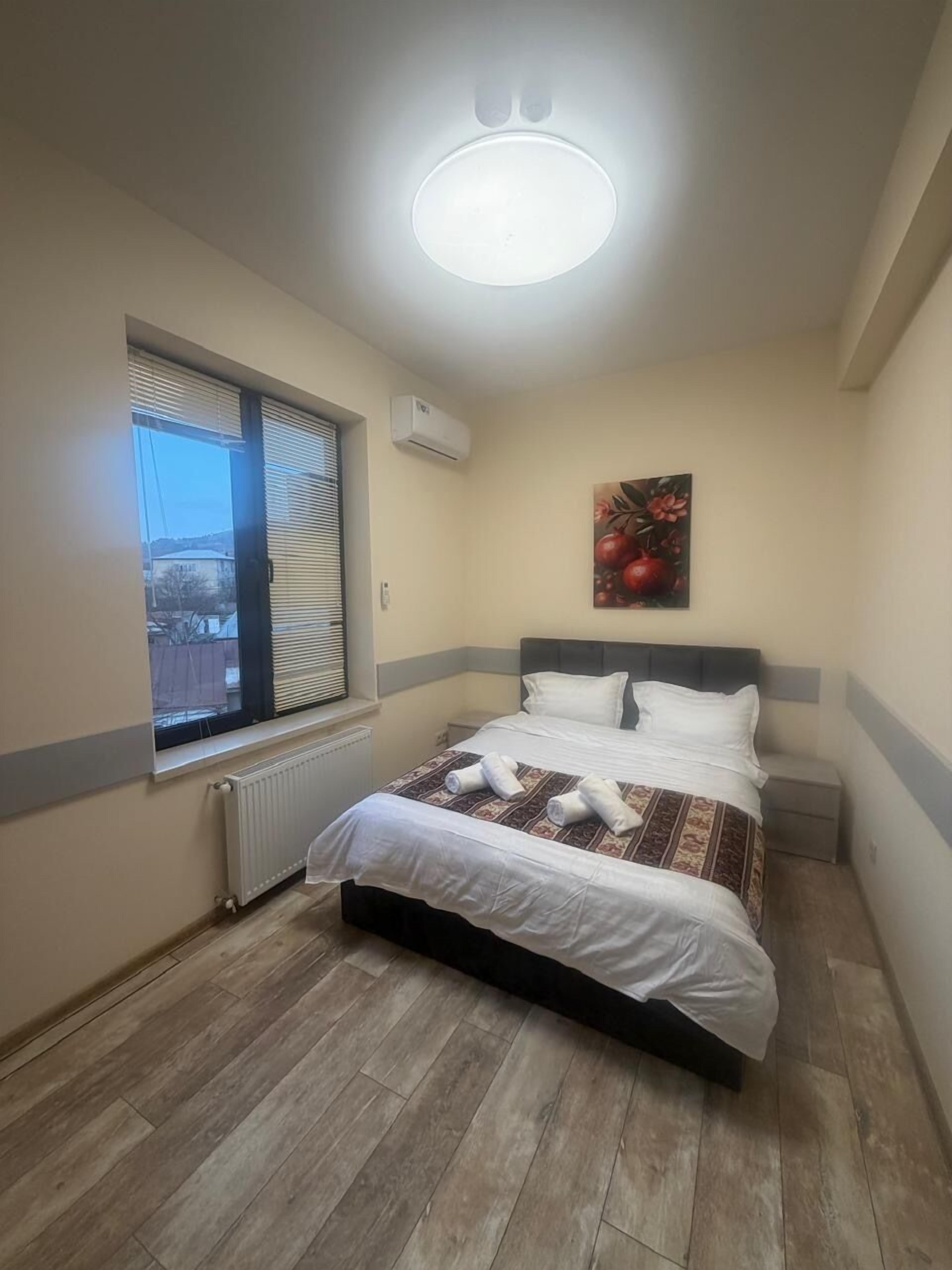A bedroom with a bed, a window, a radiator, and a ceiling light.