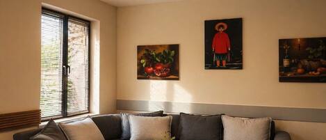 Ein Wohnzimmer mit einer Eckcouch, zwei runden Couchtischen und Kunstwerken an den Wänden.
