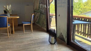 Una habitación con piso de madera, una mesa de comedor con sillas, un jarrón con flores y un mural en la pared.