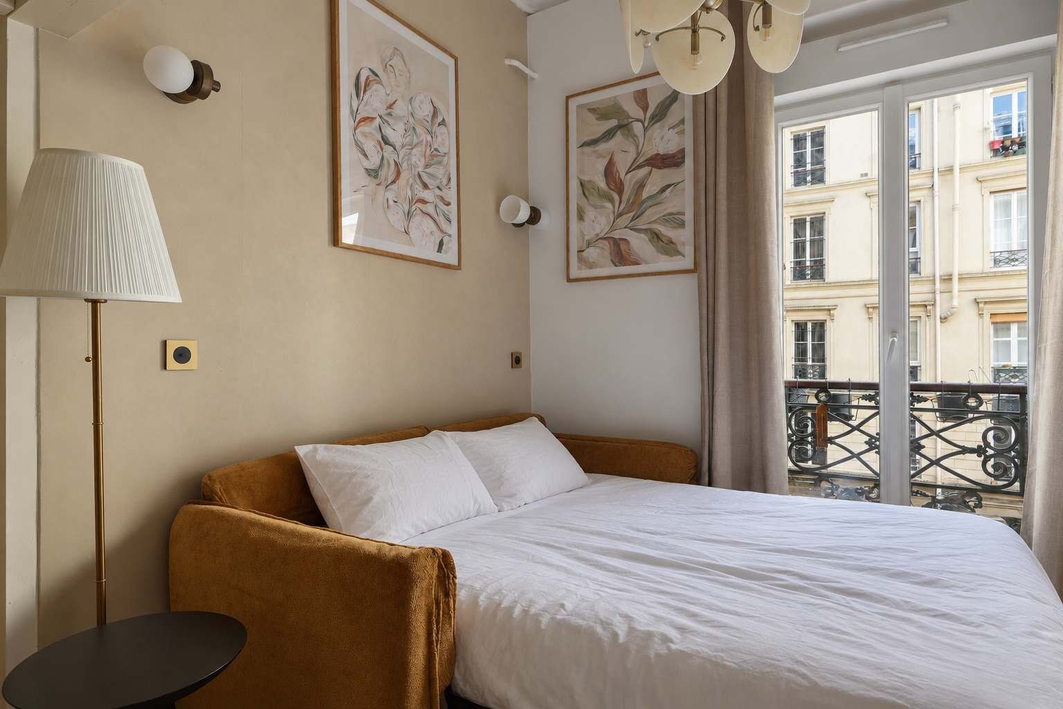 A hotel room with a bed, a lamp, and artwork on the walls.