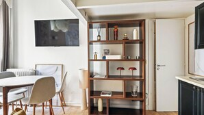 Ein modernes Wohnzimmer mit Essbereich, einer Holzbibliothek, einem Flachbildfernseher und einer Küchenzeile.