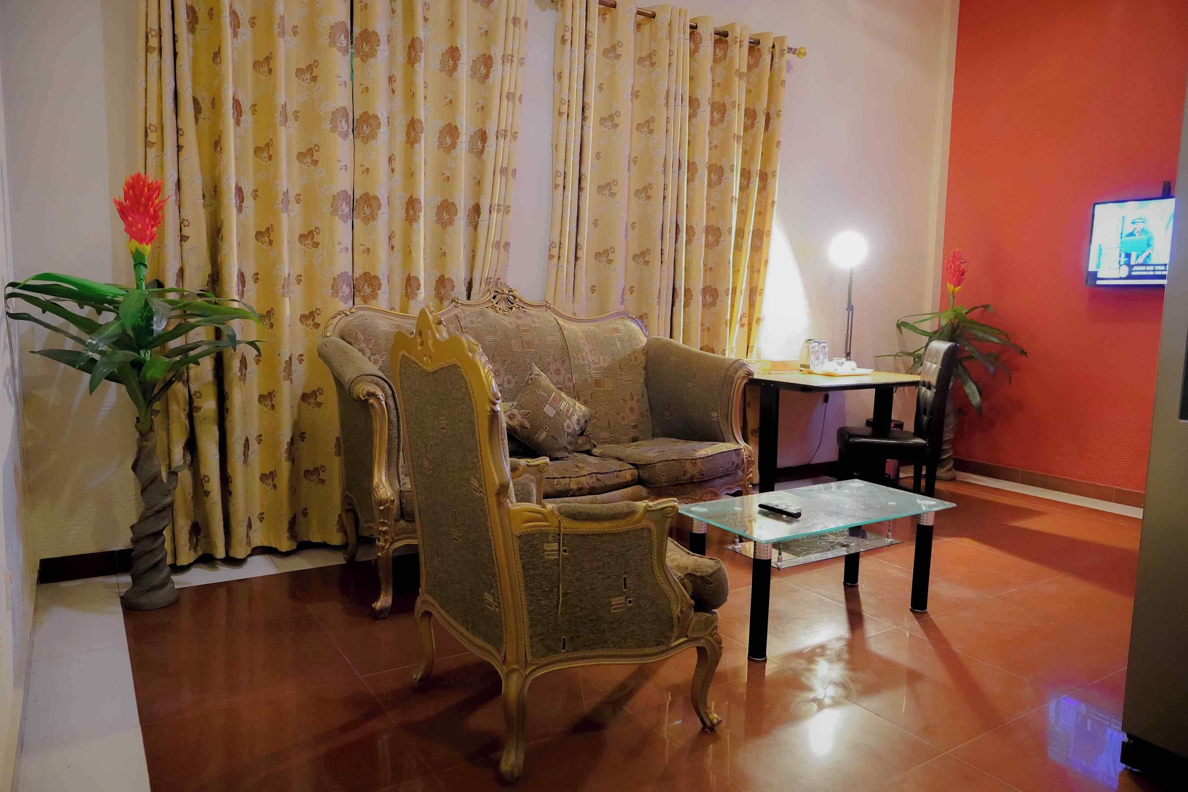 Una sala de estar con un sofá, una mesa de centro de vidrio y un televisor en la pared.