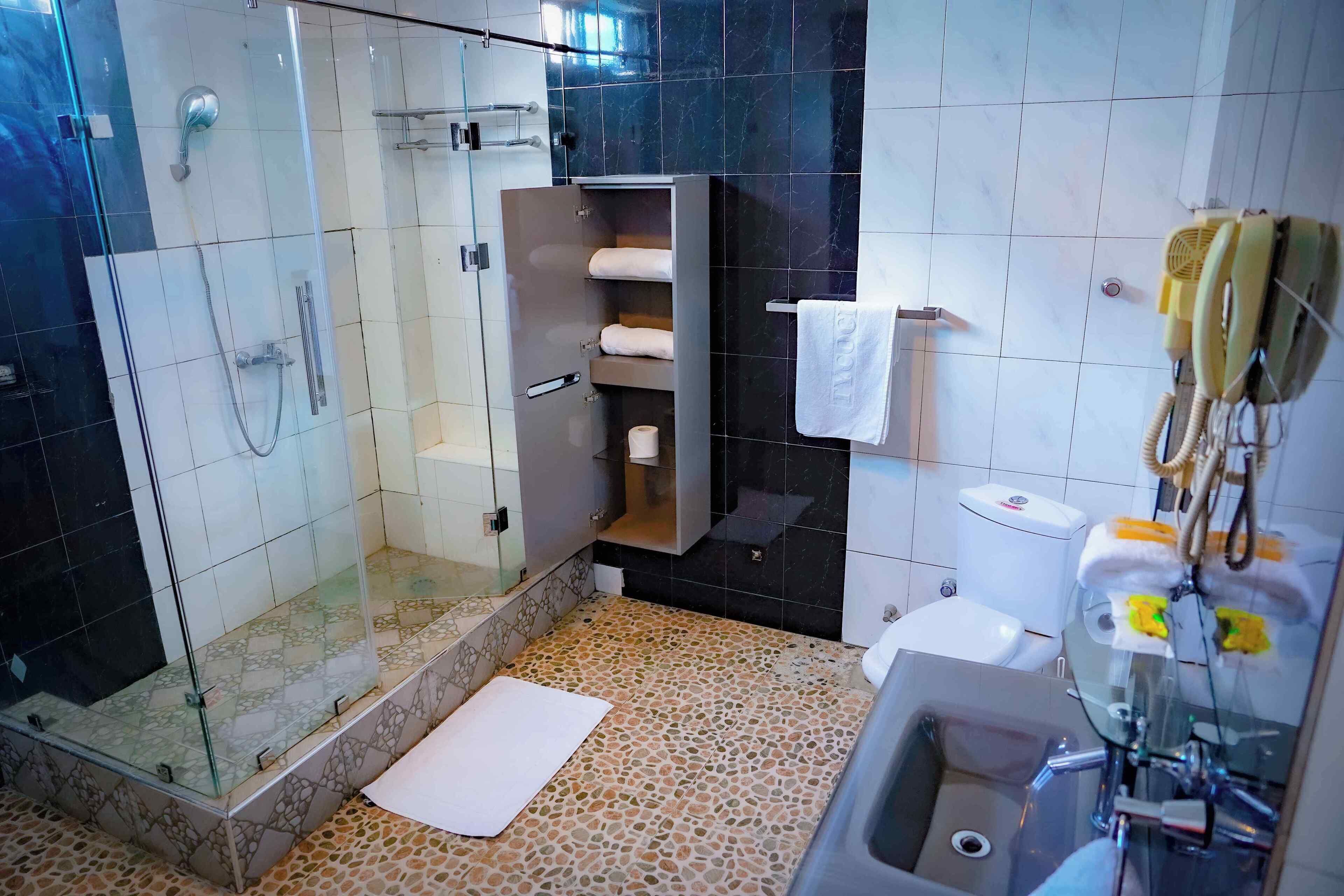 Un baño moderno con ducha envuelta en vidrio, inodoro empotrado y lavamanos con cubierta de vidrio.