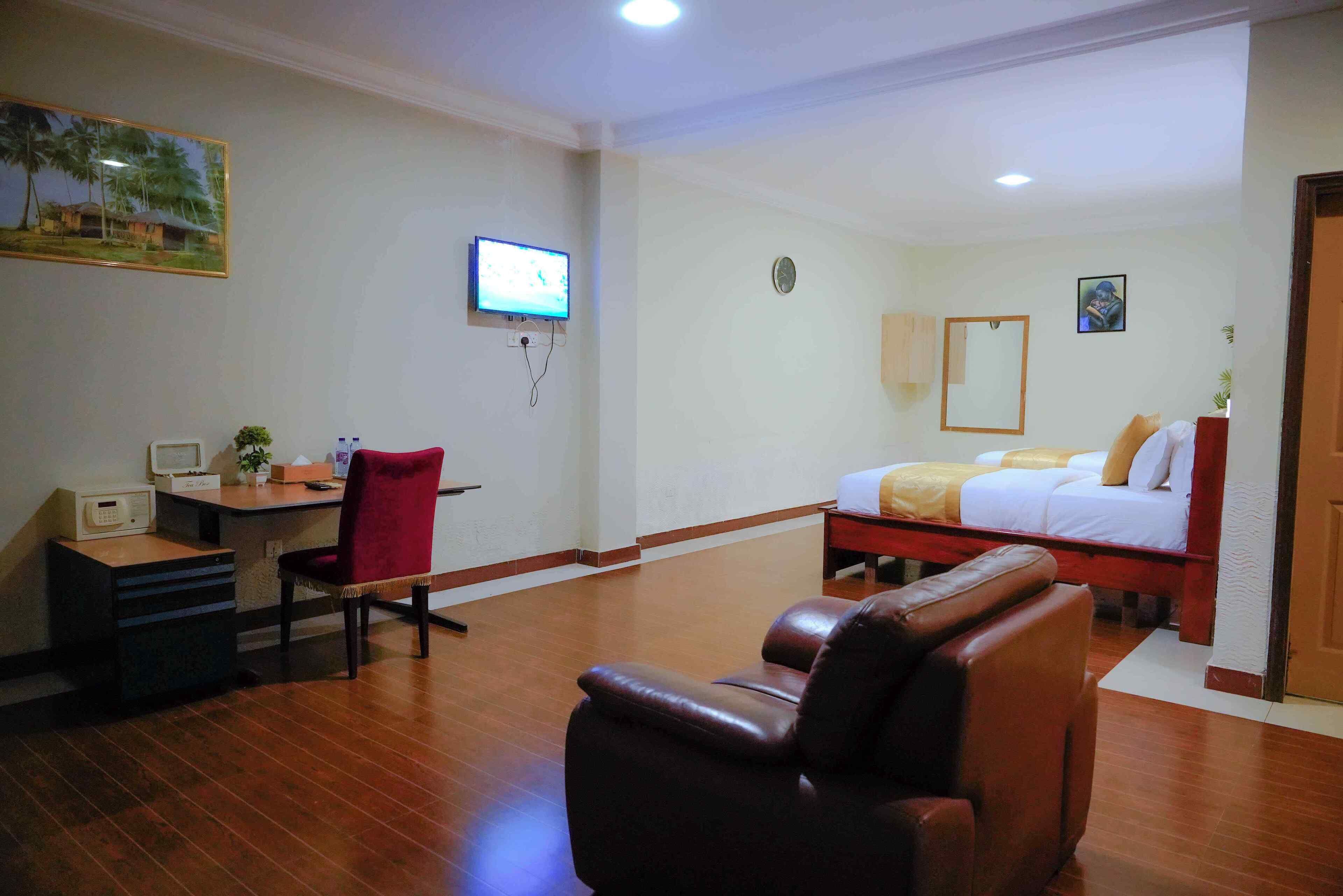 Une chambre d’hôtel équipée d’un bureau, d’une chaise, d’un fauteuil massant, d’un lit et d’une télévision.