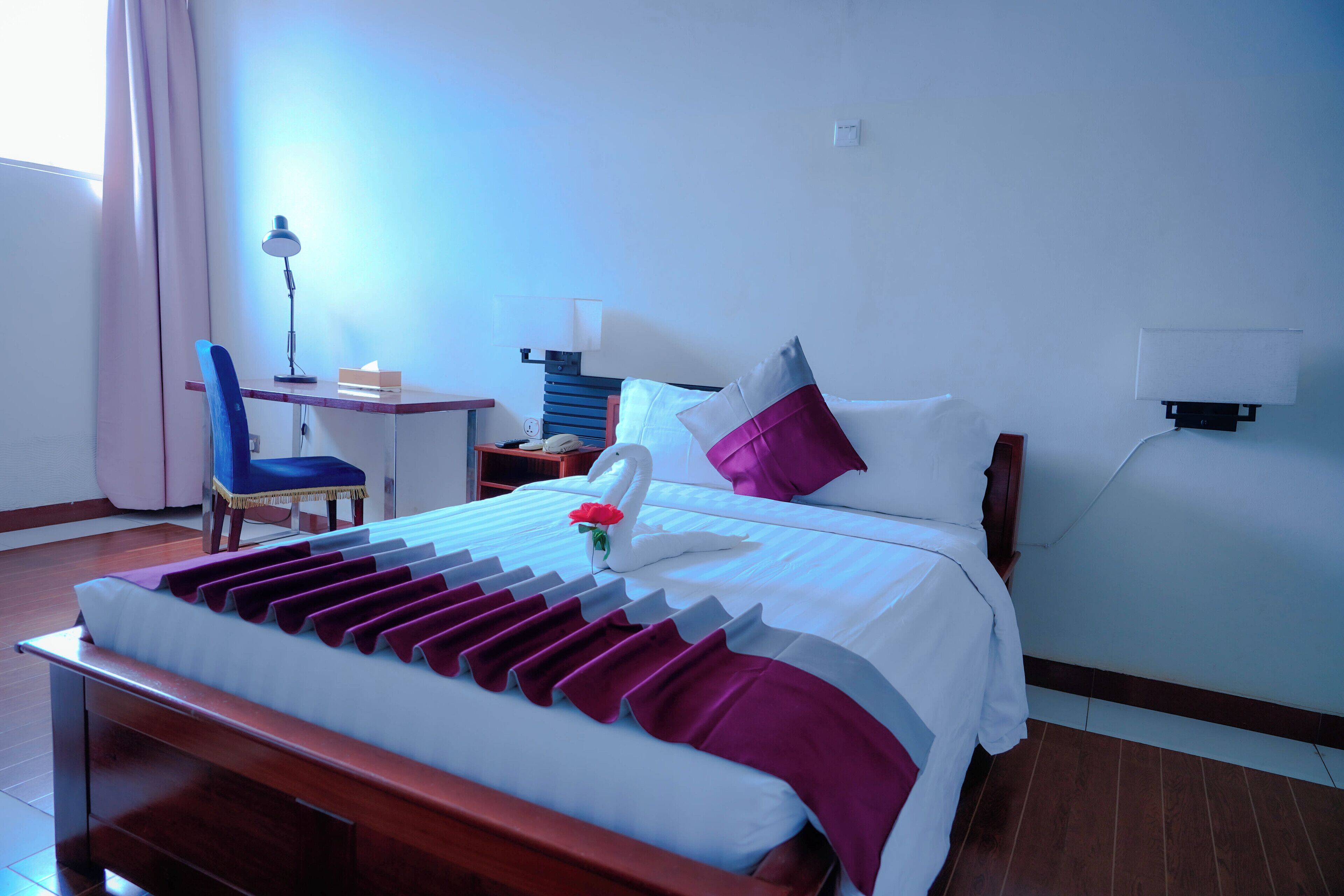 Een keurig opgemaakt hotelkamer met een bed, bureau en stoel.