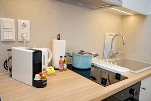 A modern kitchen with a built-in stove, a kettle, a pot, a sink, and a coffee maker. - Emily in Athens - Central balcony flat (Athina)