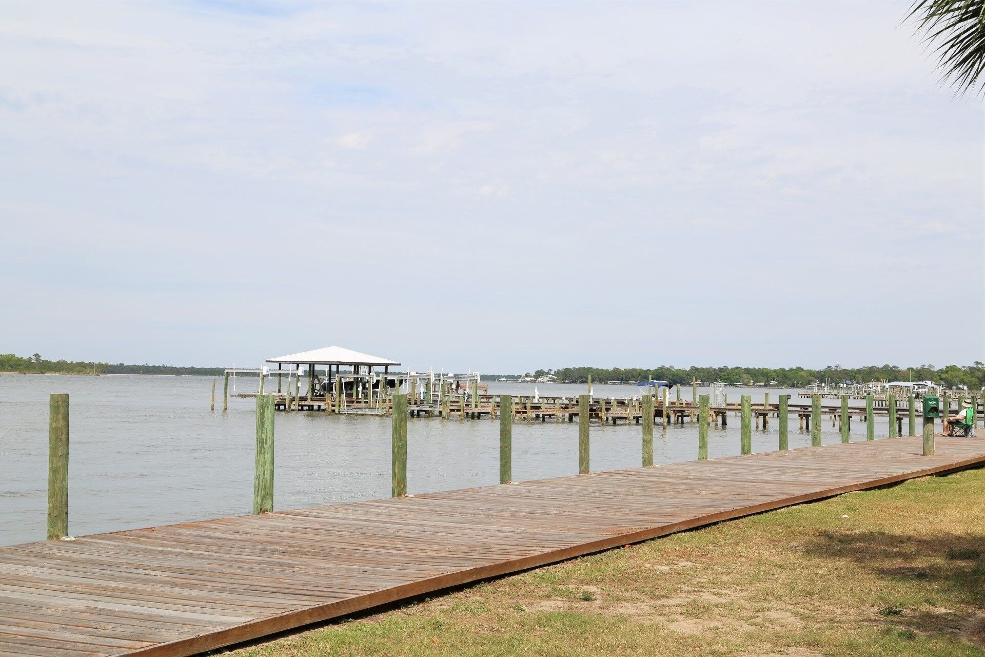 A wooden pier extending into calm water, with a small covered structure at the end.